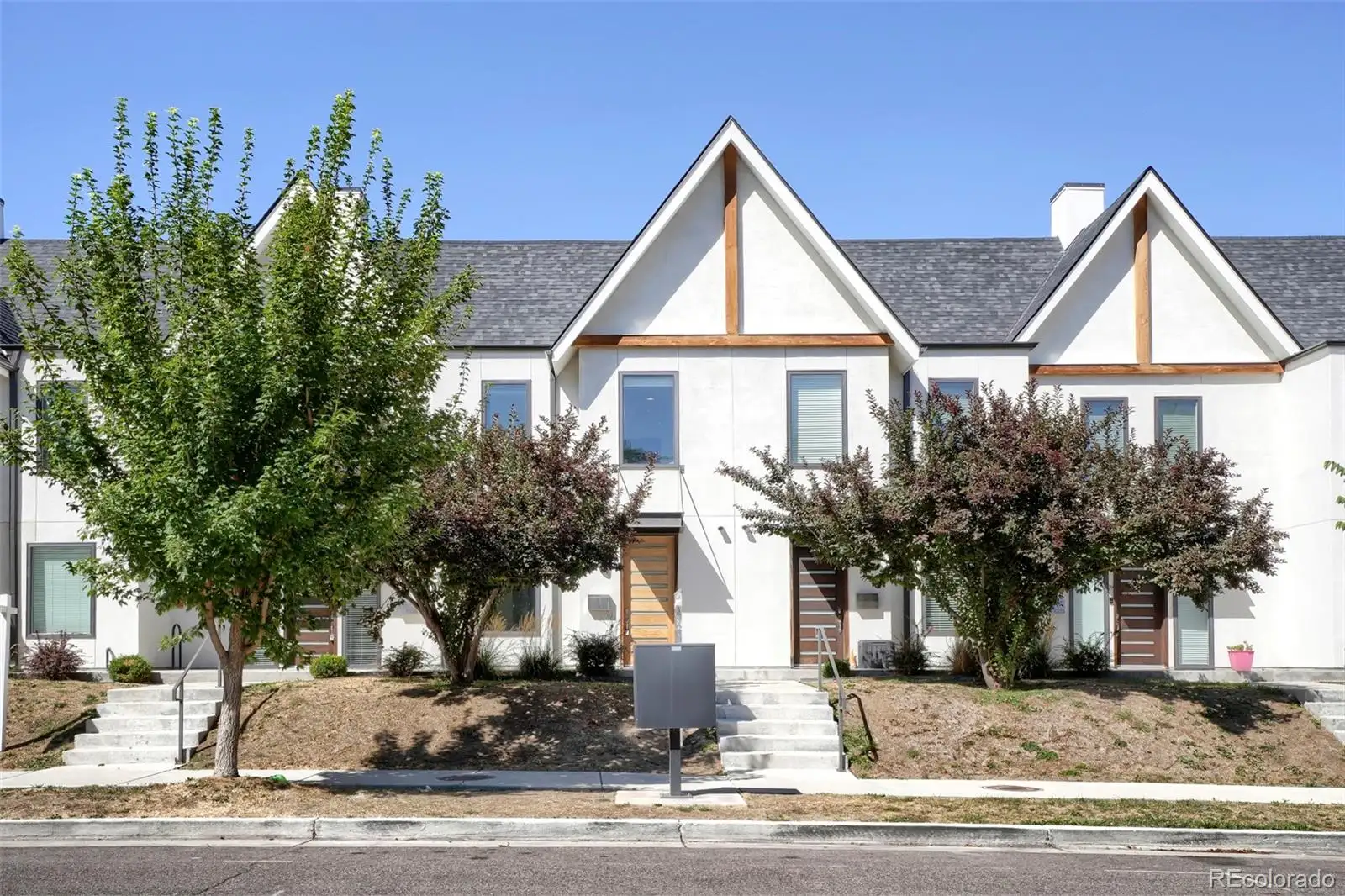 Front exterior: a row of white townhomes with timber gable accents